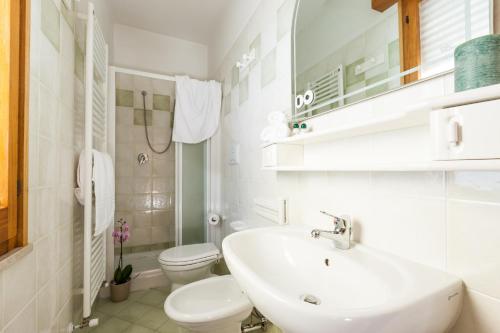 a white bathroom with a sink and a toilet at Villa dei Fiori Apartments in Cervia
