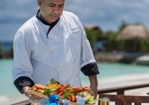 a chef preparing a plate of food on a table at Makunudu Island- An Intimate Hideaway in Makunudhoo