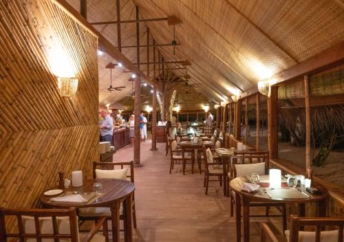 a restaurant with tables and chairs and people in the background at Makunudu Island- An Intimate Hideaway in Makunudhoo