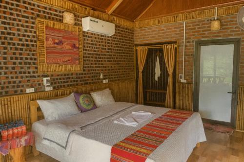 une chambre avec un lit et un mur de briques dans l'établissement Hải Nam Homestay Hòa Bình, à Mai Châu