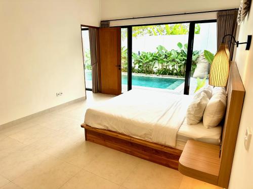 a bedroom with a bed and a sliding glass door at Villas Topazio and Opalo -- Gateway to Uluwatu beaches in Uluwatu