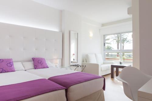 a white bedroom with a large bed with purple pillows at Hotel Albahia Alicante in Alicante