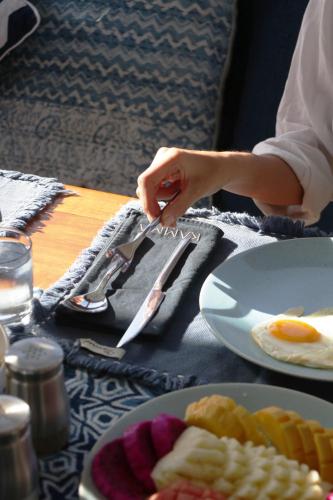 una persona que sostiene un cuchillo y un tenedor junto a platos de comida en Kamma Sail, en Labuan Bajo