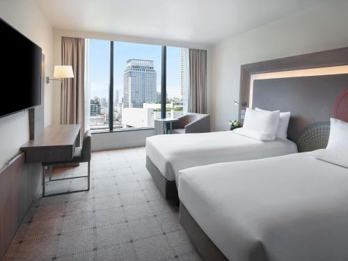 a hotel room with two beds and a large window at Novotel Bangkok Platinum Pratunam in Bangkok