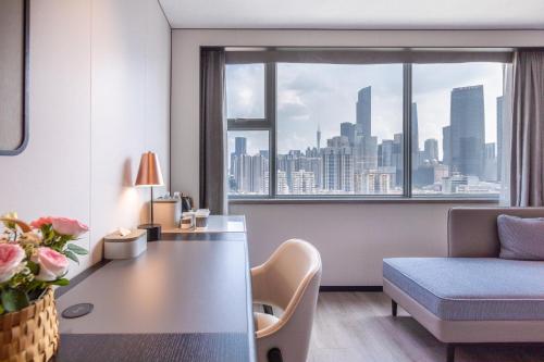 広州市にあるAtour Hotel Guangzhou Zhujiang New Town Taikoo Huiのデスク、ベッド、窓が備わるホテルルームです。