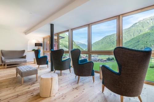 a room with chairs and a table with a view of mountains at Tonzhaus Hotel in Senales