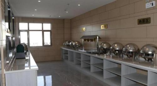 a kitchen with a row of silver pots and pans at Green Tree Inn Express Inner Mongolia Ulan Qab High-Speed Railway Station in Ulanqab