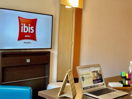 a laptop computer sitting on a desk with a television at ibis Medellin in Medellín