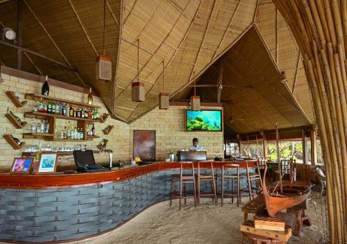 a restaurant with a bar with a tv on the wall at Makunudu Island- An Intimate Hideaway in Makunudhoo