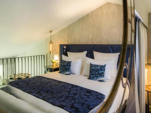 a bedroom with a bed with blue and white pillows at La Grande Terrasse Hotel & Spa La Rochelle - MGallery Collection in Châtelaillon-Plage