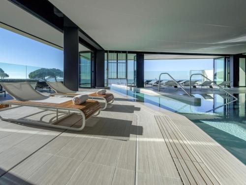 a swimming pool with several beds in a building at La Grande Terrasse Hotel & Spa La Rochelle - MGallery Collection in Châtelaillon-Plage