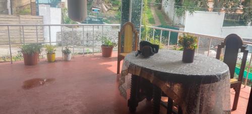a balcony with a table and potted plants on it at VHP luxury cottage kodaikkanal in Kodaikānāl