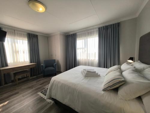 a bedroom with a large white bed and windows at Harmonie in Hartenbos in Mossel Bay