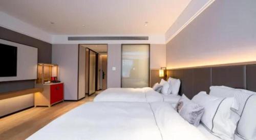 a large bedroom with a large white bed and a flat screen tv at Echeng Hotel Nanning the Mixc Convention in Nanning
