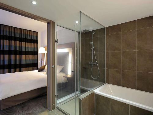 a bathroom with a shower and a bed and a tub at Novotel Avignon Centre in Avignon