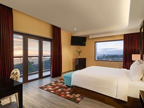 a hotel room with a bed and a large window at Mercure Padang in Padang