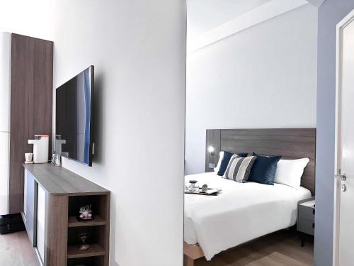 a bedroom with a white bed and a mirror at Ibis Hong Kong Central & Sheung Wan in Hong Kong