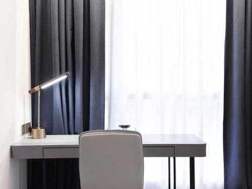 a desk with a chair in front of a window at Ibis Hong Kong Central & Sheung Wan in Hong Kong
