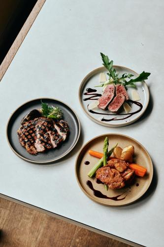 drei Teller mit Fleisch und Gemüse auf einem Tisch in der Unterkunft WPÜ HOTEL HAKONE in Hakone