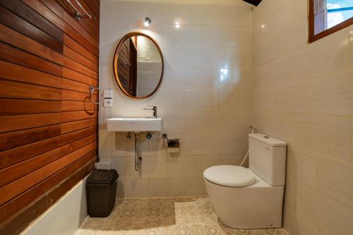 Un baño con inodoro, lavabo y espejo. en Sang Mong Ubud, en Ubud