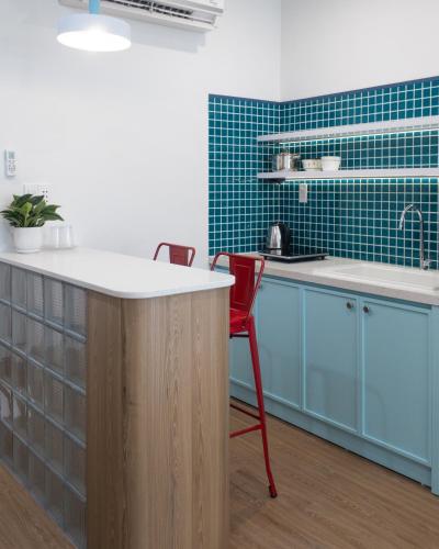 a kitchen with blue cabinets and a counter with a red chair at Mik Stay in Danang