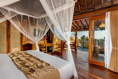 un dormitorio con una cama con dosel en Kamania Villa Ubud by Dhananjaya Hospitality, en Tampaksiring