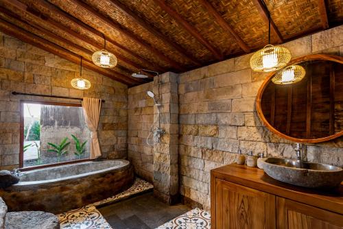 Un baño con una bañera grande y un lavabo. en Kamania Villa Ubud by Dhananjaya Hospitality, en Tampaksiring