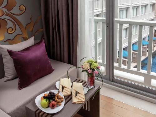 a hotel room with a table with a plate of food at Grand Mercure Phuket Patong in Patong Beach