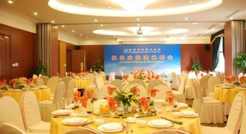 a banquet hall with white tables and white chairs at Zhangjiagang Guomao Hotel in Zhangjiagang