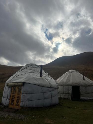 two tents in a field under a cloudy sky at GUEST HOUSE EcoNest & HORSE RIDING TOURS TO SONG-KOL LAKE in Kyzart