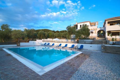 a swimming pool with chairs and a house at Petra Natura in Limenaria