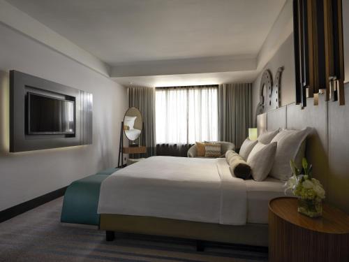 a hotel room with a large bed and a television at Pullman Jakarta Indonesia in Jakarta