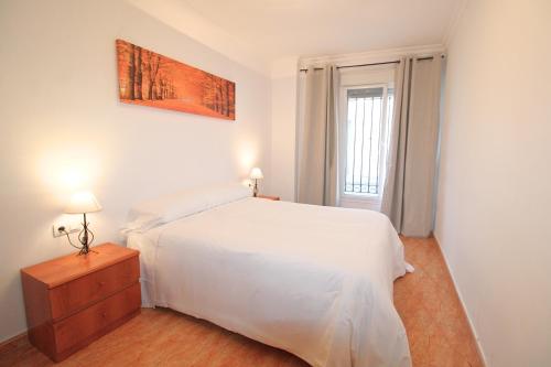 Un dormitorio con una cama blanca y una ventana. en Apartamento Tenerías Gruta by SIERRA VIVA, en Aracena