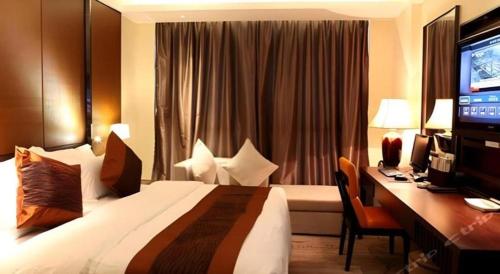 a hotel room with a bed and a desk with a computer at Excemon Yuyao Hemudu Hotel in Ningbo
