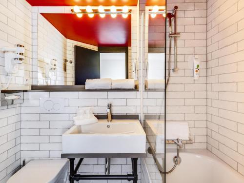 a white bathroom with a sink and a bath tub at Ibis Styles Paris Saint Denis La Plaine in Saint-Denis