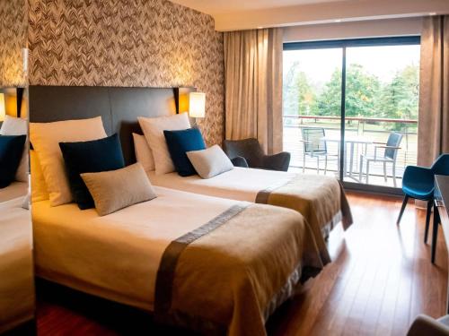 two beds in a hotel room with a balcony at Parc Beaumont Hôtel & Spa Pau - MGallery Collection in Pau