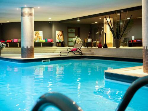 a large swimming pool in a hotel lobby at Parc Beaumont Hôtel & Spa Pau - MGallery Collection in Pau