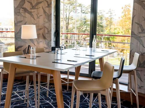 a table and chairs in a room with a large window at Parc Beaumont Hôtel & Spa Pau - MGallery Collection in Pau