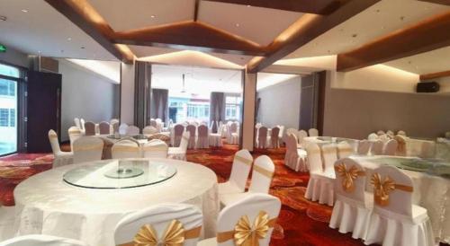 a banquet hall with white tables and white chairs at Huangshan Shuguang Yusong Hotel in Huangshan