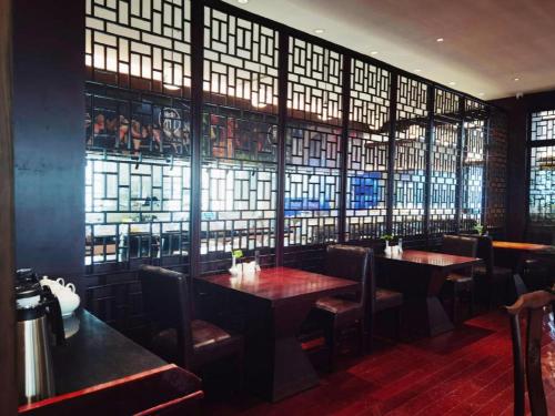 a restaurant with two tables and chairs and windows at Huangshan Shuguang Yusong Hotel in Huangshan
