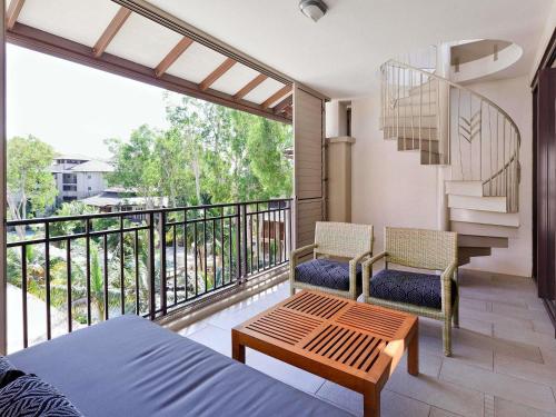 una camera da letto con balcone con un letto e una scala di Pullman Palm Cove Sea Temple Resort & Spa a Palm Cove