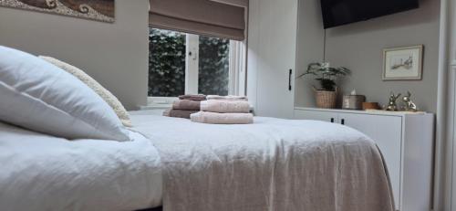 Un dormitorio con una cama blanca con toallas. en Tiny Villa de Haas met Infraroodsauna, en Egmond aan Zee