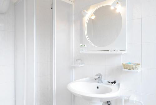 W białej łazience znajduje się umywalka i lustro. w obiekcie Sporting Hotel Stella Maris w mieście Bosa Marina