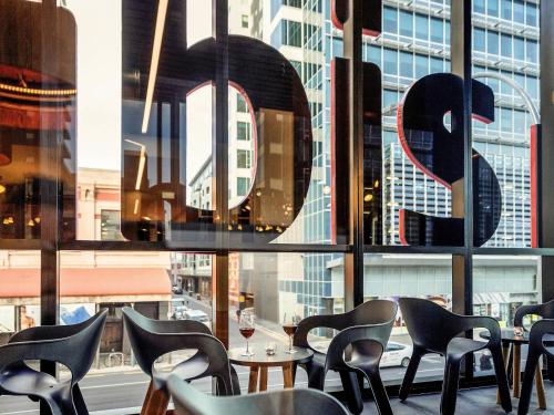 a restaurant with tables and chairs in front of a window at ibis Adelaide in Adelaide