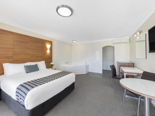 a hotel room with a bed and a desk and a table at Mercure Wagga Wagga in Wagga Wagga