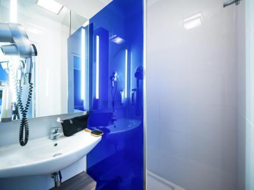 a blue bathroom with a sink and a shower at ibis Styles St Gilles Croix de Vie centre-ville in Saint-Gilles-Croix-de-Vie