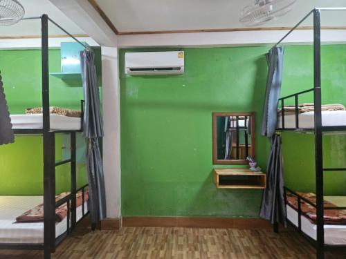 a room with four bunk beds and a green wall at LPQ Hostel in Luang Prabang