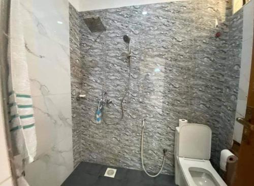 a bathroom with a shower with a stone wall at Estancia Residences Naguru in Kampala