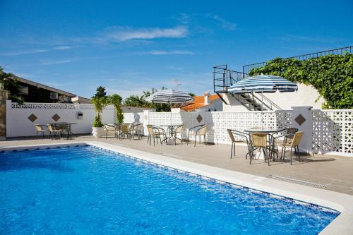 einen Pool mit Tischen und Stühlen sowie einem Tisch und einem Sonnenschirm in der Unterkunft Ona Aldea del Mar in Torrevieja