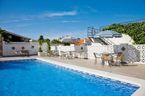 a swimming pool with tables and chairs and a table and umbrella at Ona Aldea del Mar in Torrevieja